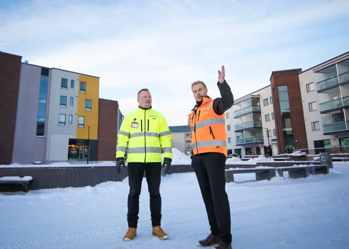 Seppo Saaristo ja Anders Eklund seisovat lumisella pihalla kerrostalojen edessä