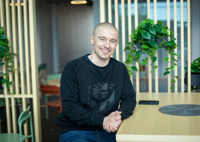 Hymyilevä Oskari Saarinen istumassa pöydän ääressä