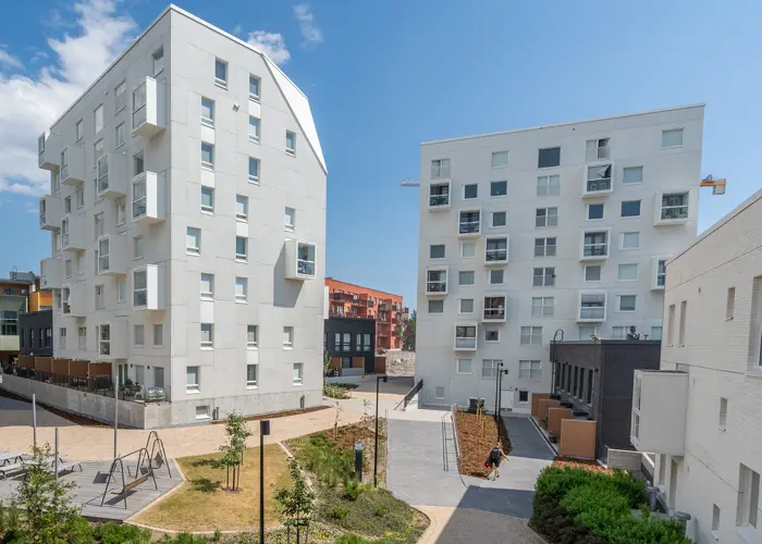 Hartelan rakentamat kaksi vaaleaa kerrostaloa, rivitalo ja sisäpihan oleskelualue Helsingin Kruunuvuorenrannassa.