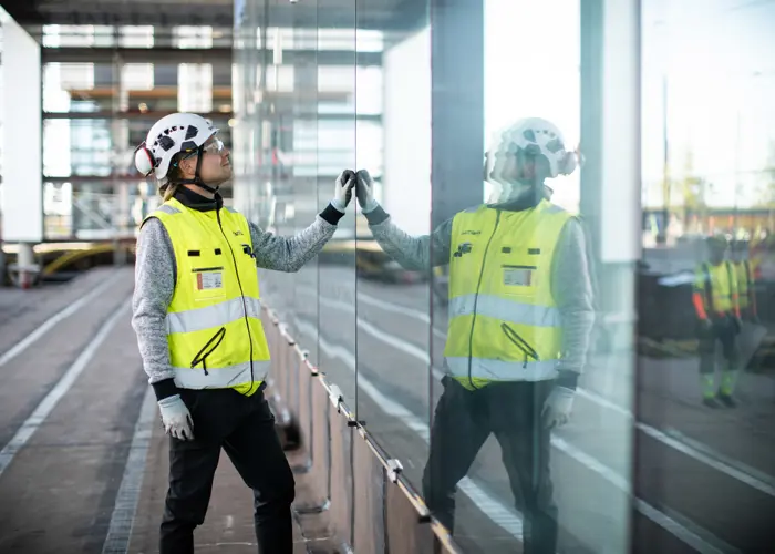 Joni Lomakin seisoo rakennusvaatteet päällä heijastavaa pintaa kohden