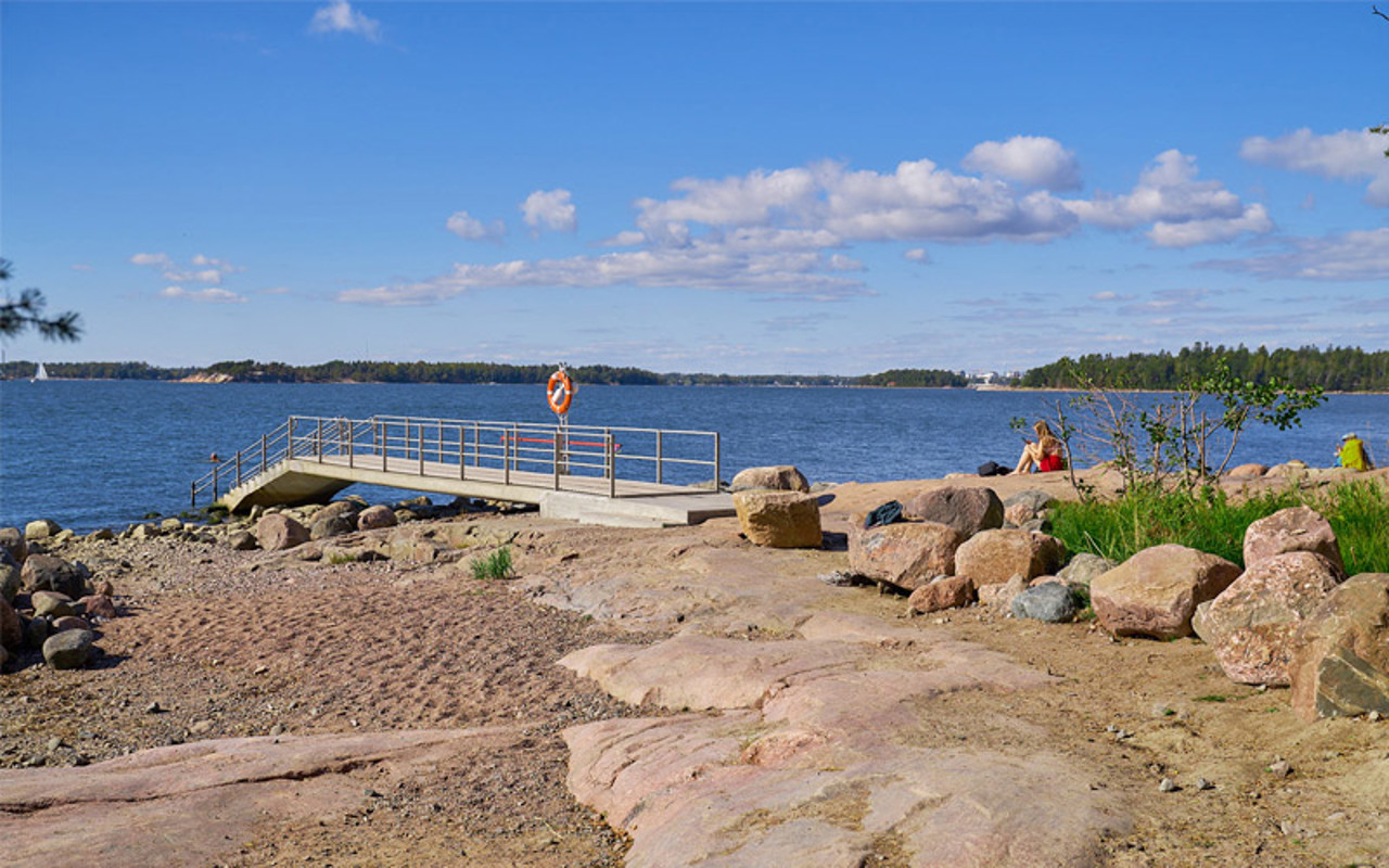 Valokuvanäkymä Lauttasaaressa sijaitsevasta kalliorannasta, jossa on laituri