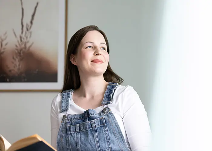 Nuori nainen katsoo kaihoisasti ulos Hartelan rakentamassa kodissa